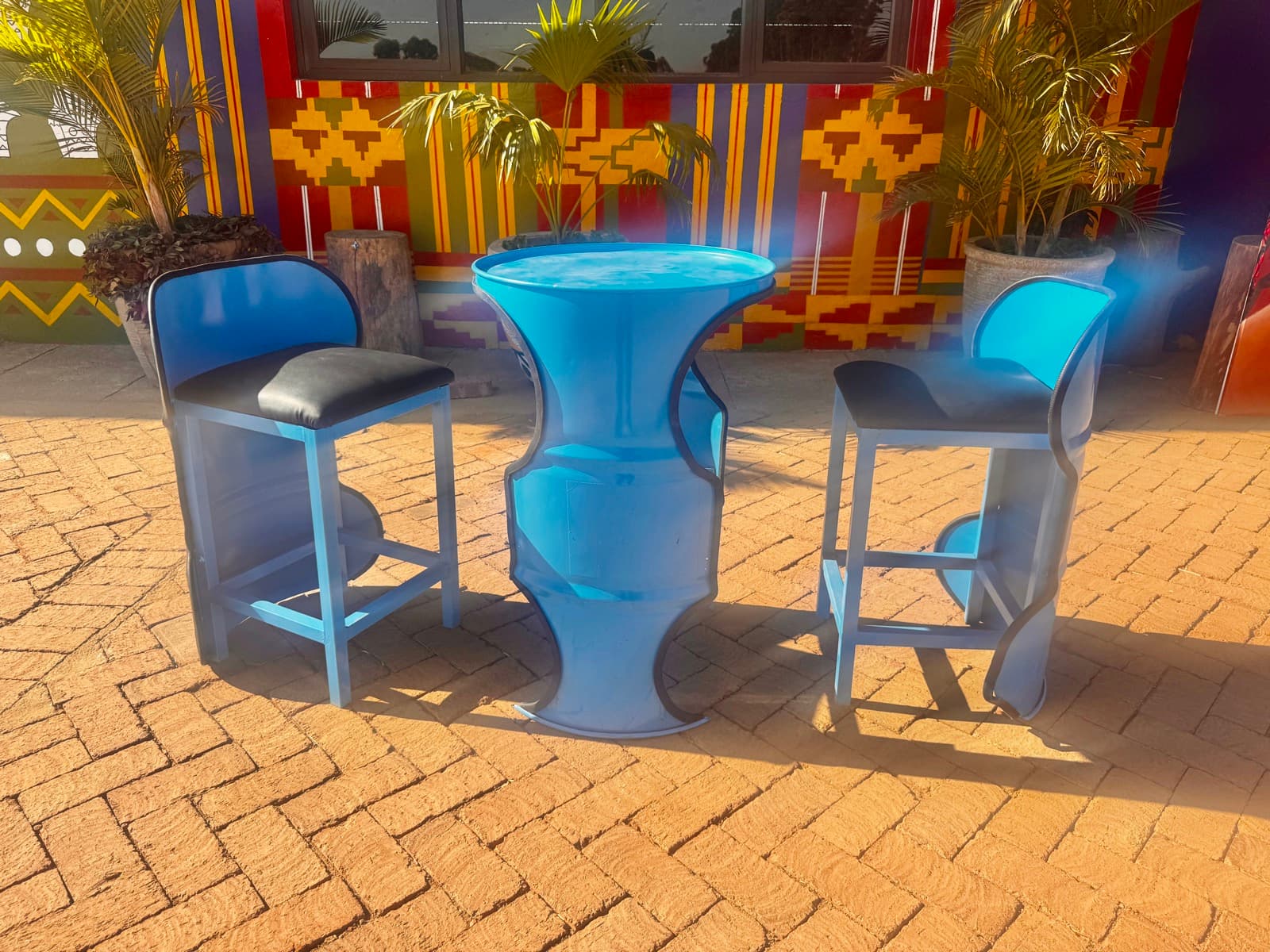 A barrel bar table and stools against a painted wall