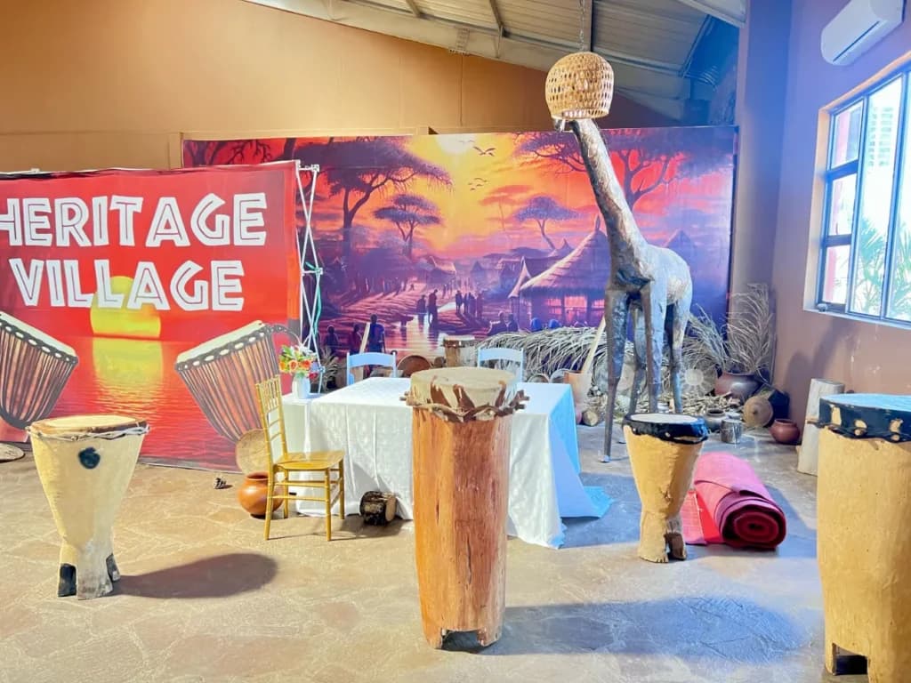 A giraffe sculpture and drums by the Heritage Village banner